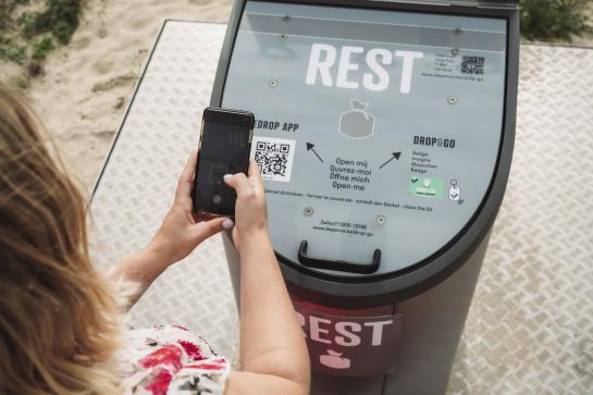 Een persoon scant de QR code op de afvalcontainer