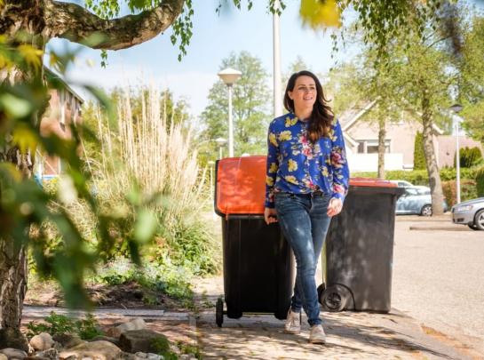 Handelaar met een afvalcontainer met oranje deksel