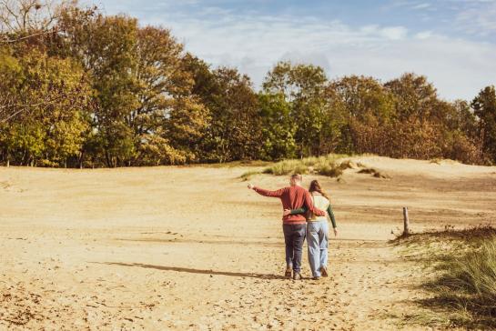 een koppel wandelt in de duinen tijdens de herfst